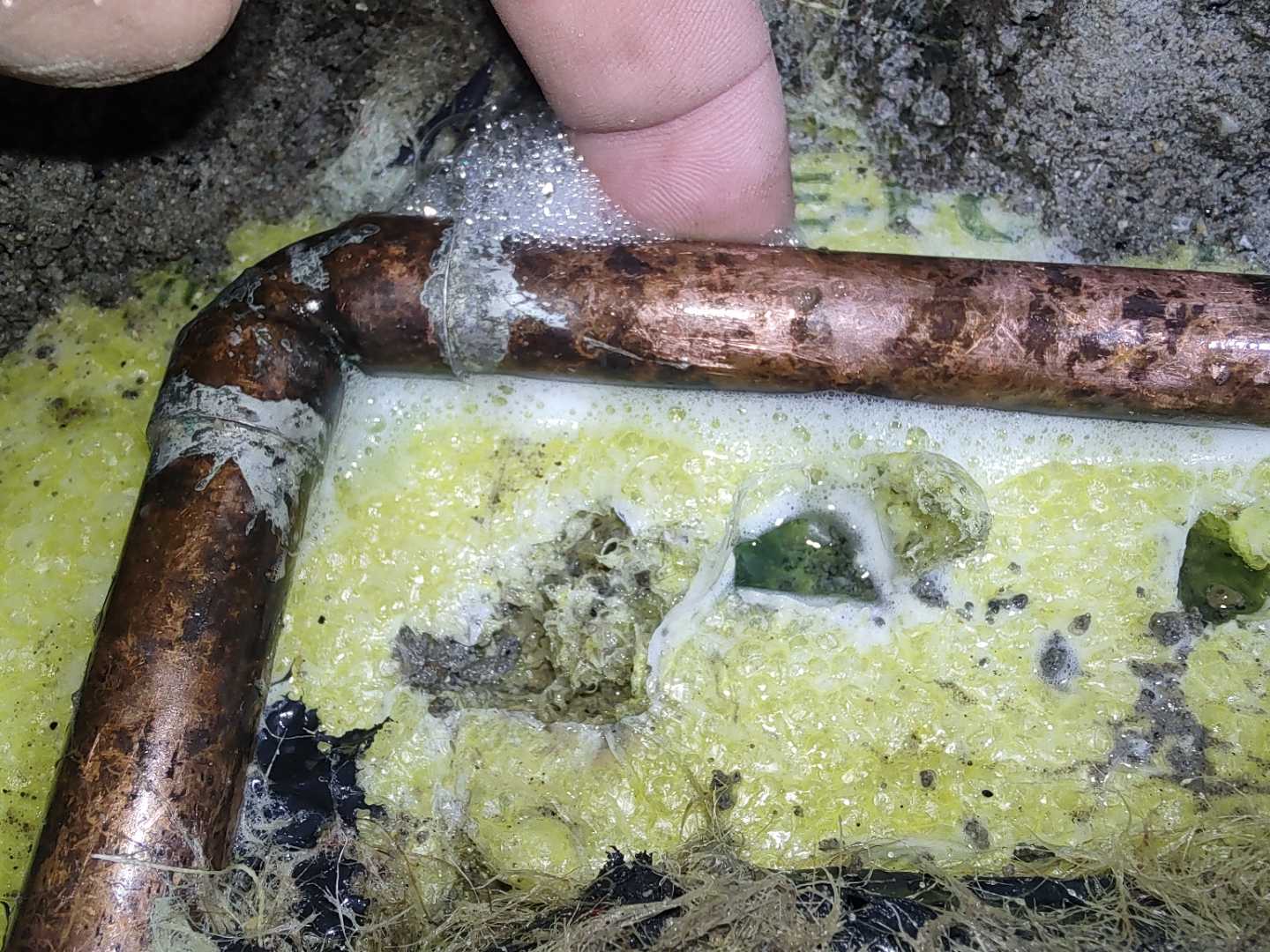 Exposed copper pipe and elbow surrounded by insulation and foam
