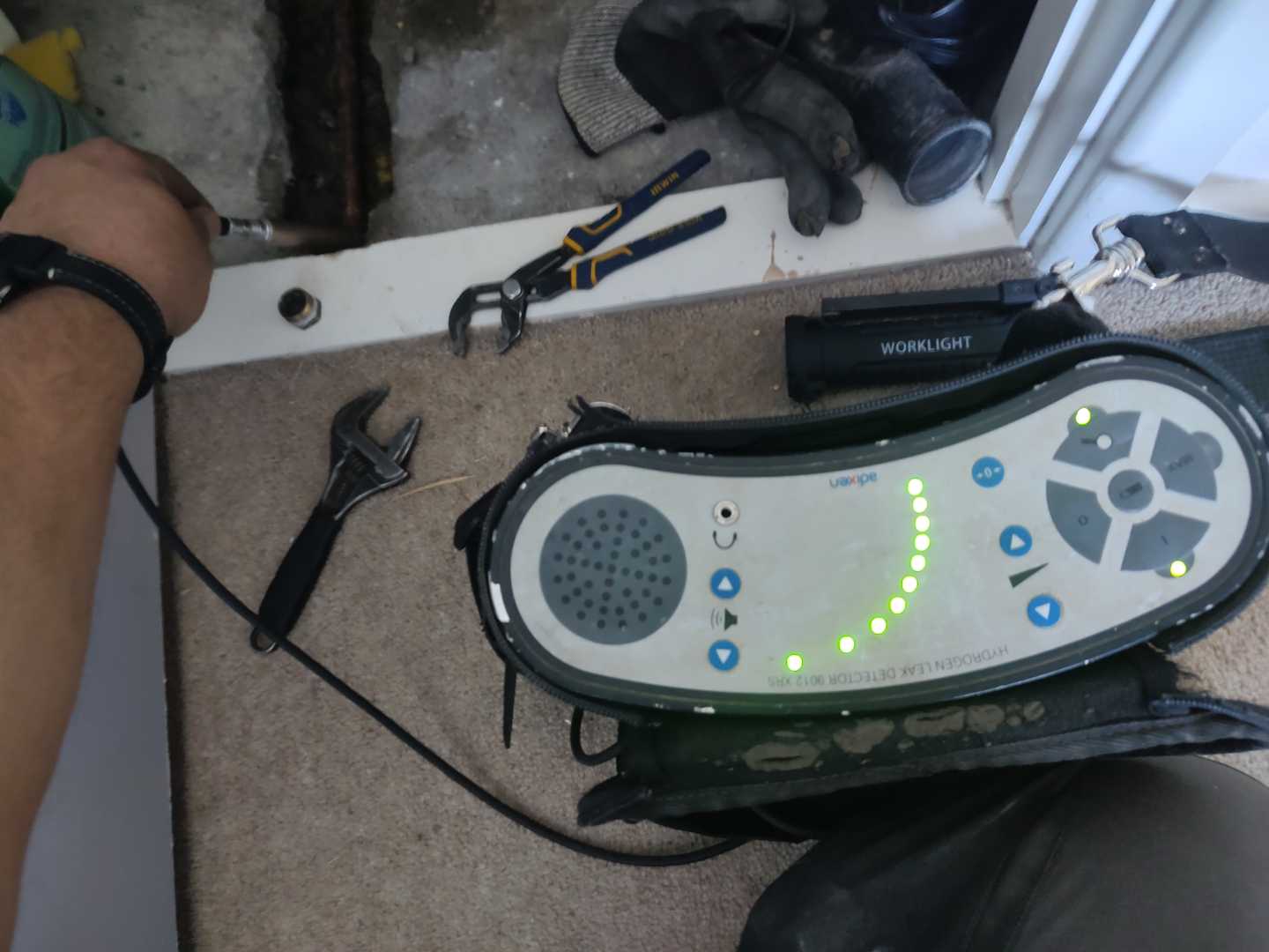 Tracer-gas detection instrument beside tools and opened flooring